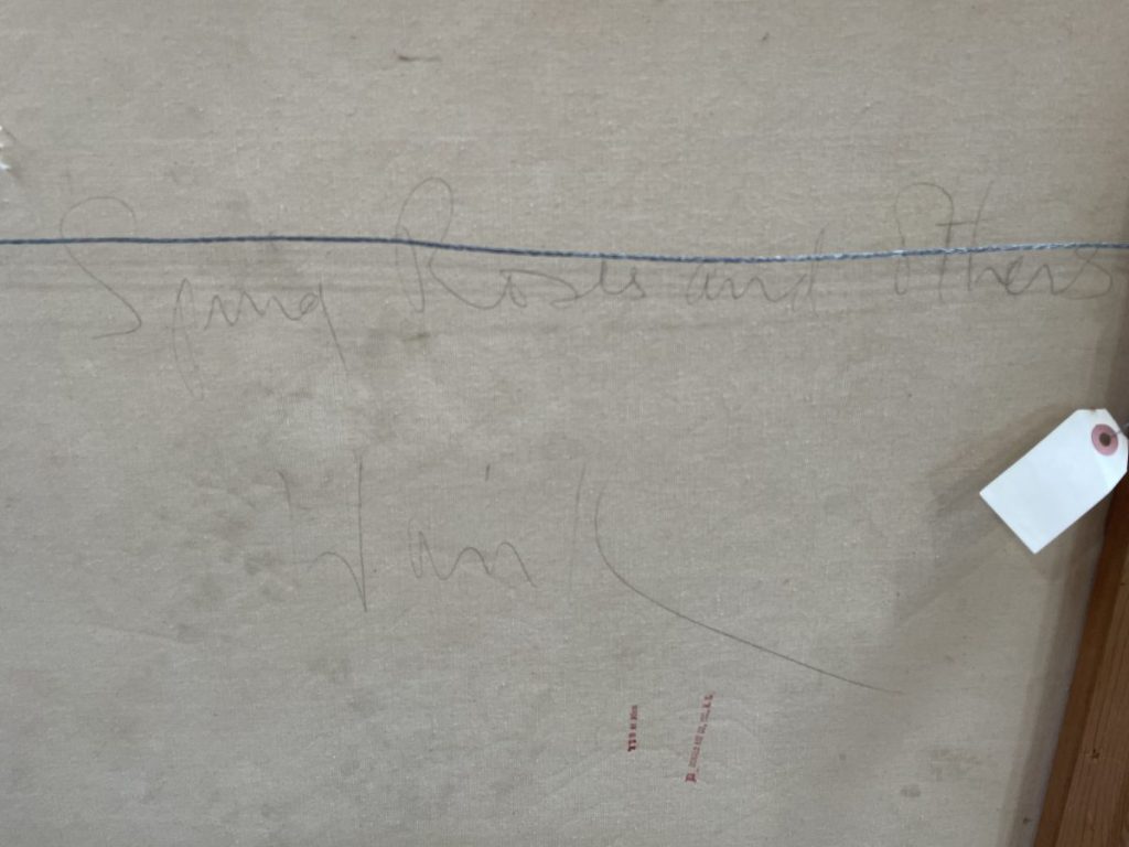 Faint handwritten notes on a canvas surface with a tag attached.