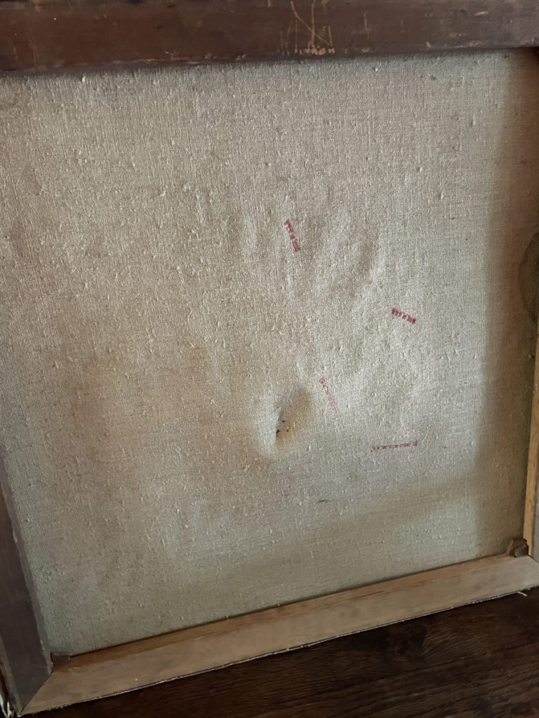 Back of a canvas showing a handprint impression and red markings on the fabric.