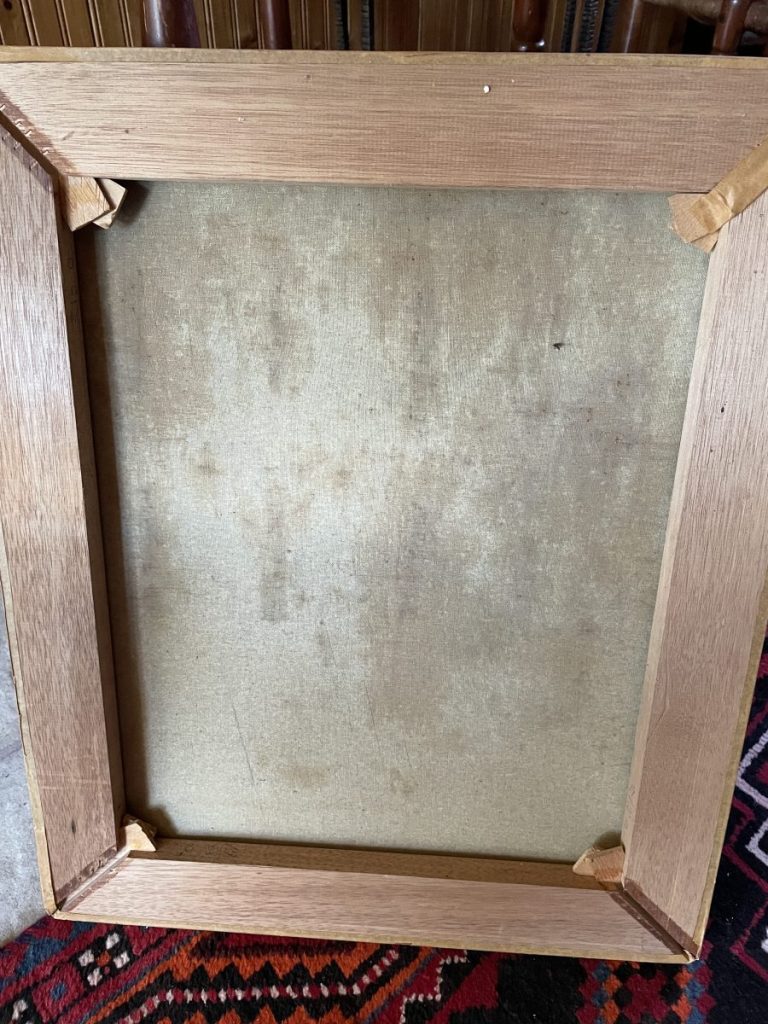 Backside view of a wooden picture frame with a textured backing and corner supports.