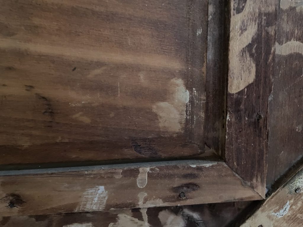 Close-up of a wooden frame showing a textured surface with visible paint marks and wear.