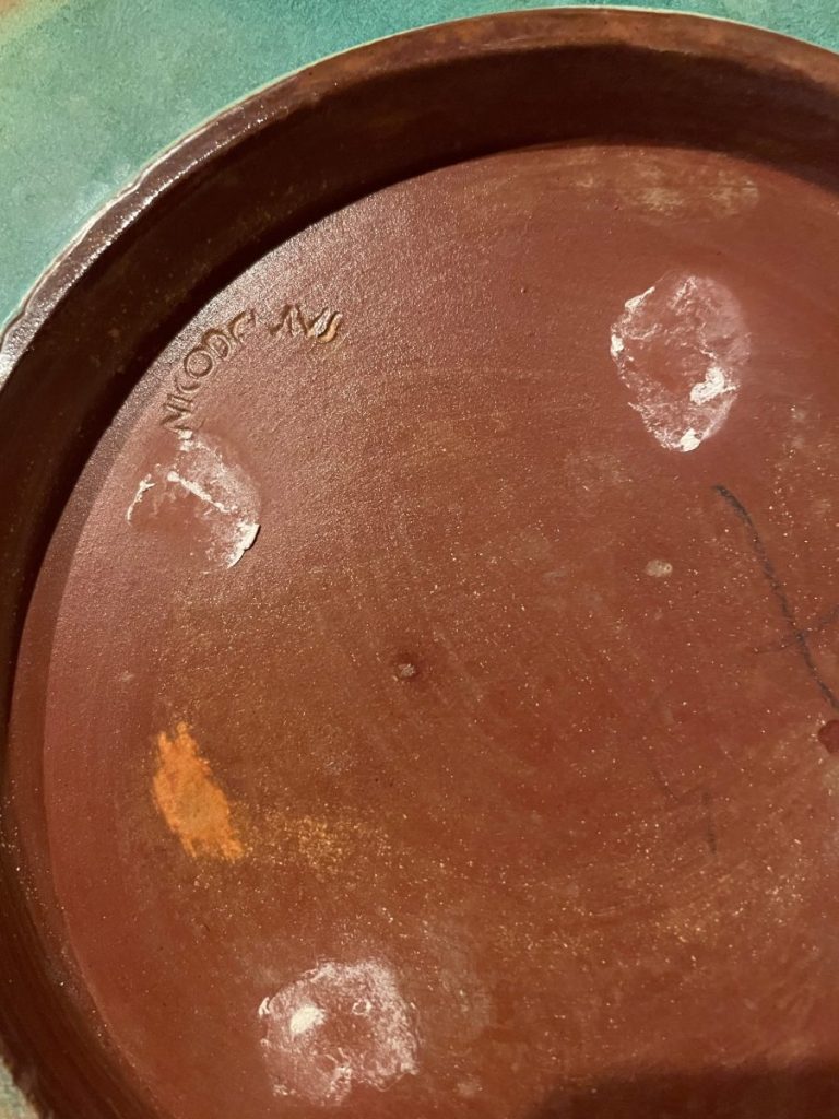 Bottom view of a terracotta pot showing marks and inscriptions on the surface.