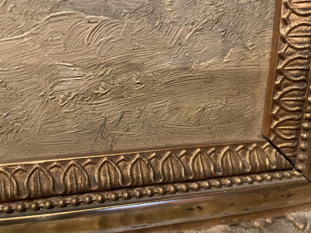 Close-up of an ornate picture frame with intricate gold detailing and textured surface.