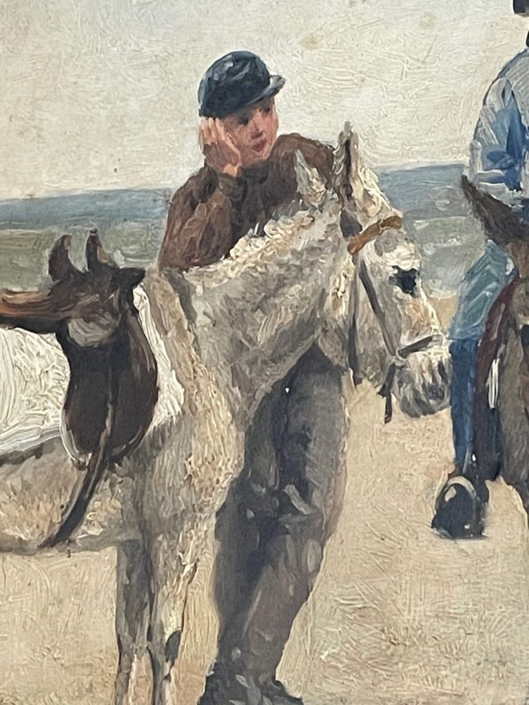 A young man in a brown sweater stands beside two horses, one white and one brown, with a hand on his face.