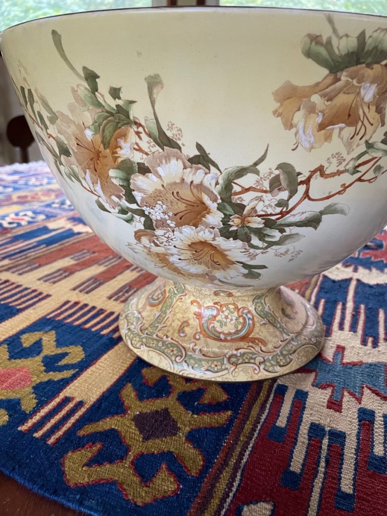 Ceramic bowl with floral designs in soft colors, featuring a decorative base.