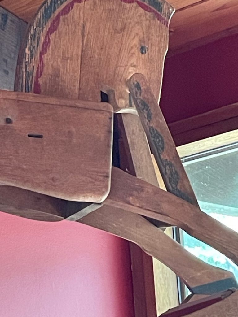Close-up of a wooden chair featuring a rustic design and visible wear on the surface.