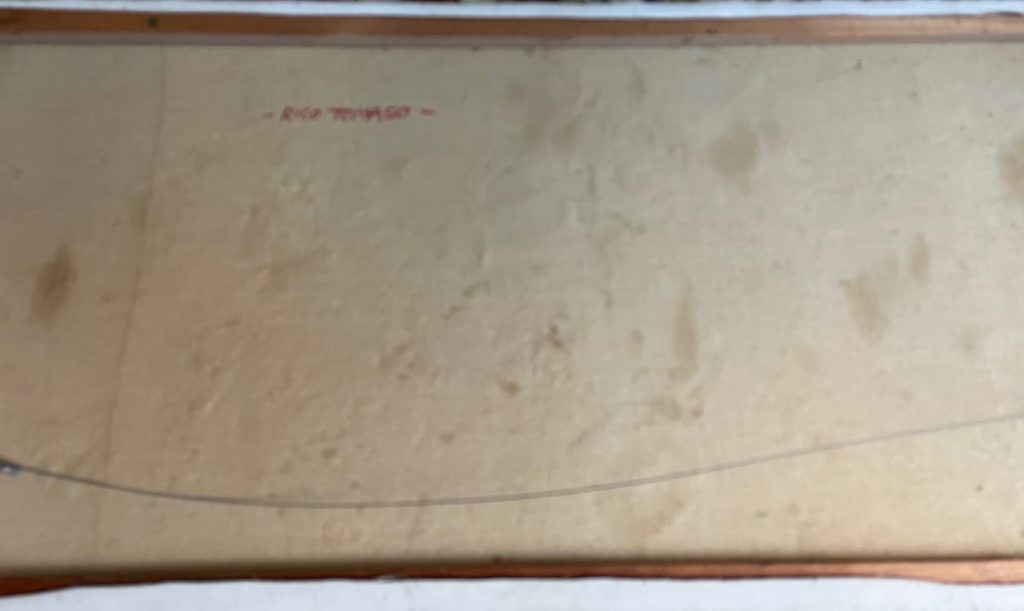 Back of a framed artwork showing a plain backing board with some markings.