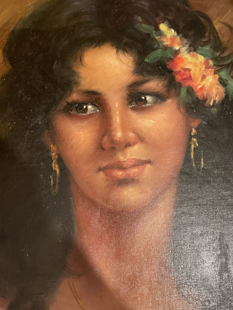 Portrait of a woman with dark hair and a floral accessory in her hair, wearing earrings.