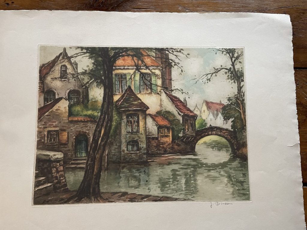 Watercolor artwork depicting a quaint European village with a bridge over a river.
