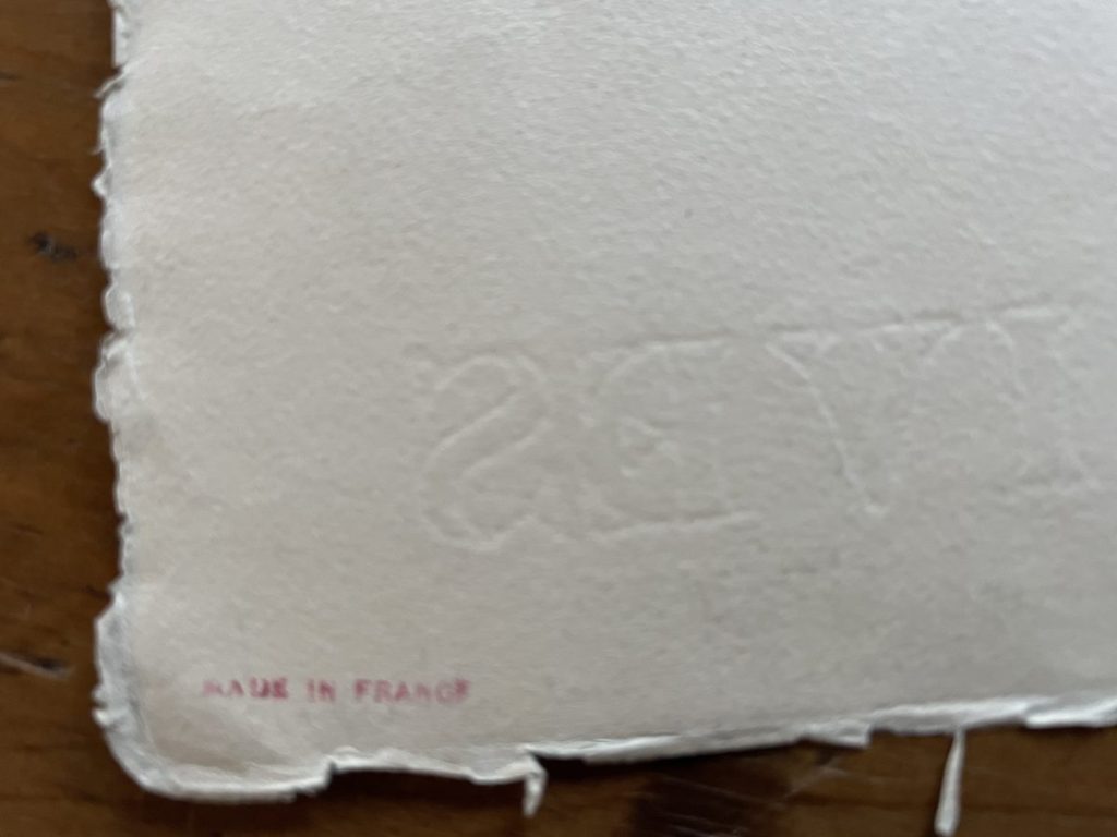 Close-up of textured paper showing embossed text and a 'Made in France' marking.