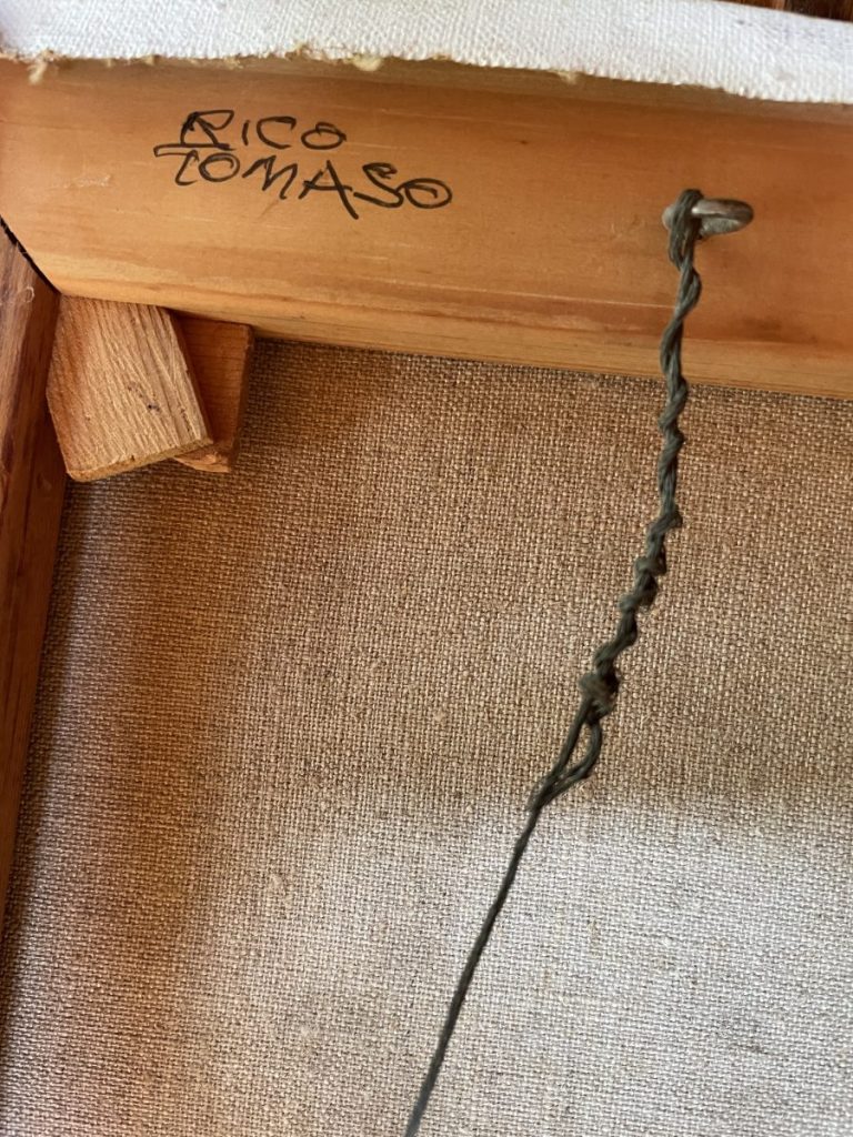 Signature of artist Rico Tomaso on the wooden frame of a canvas painting.