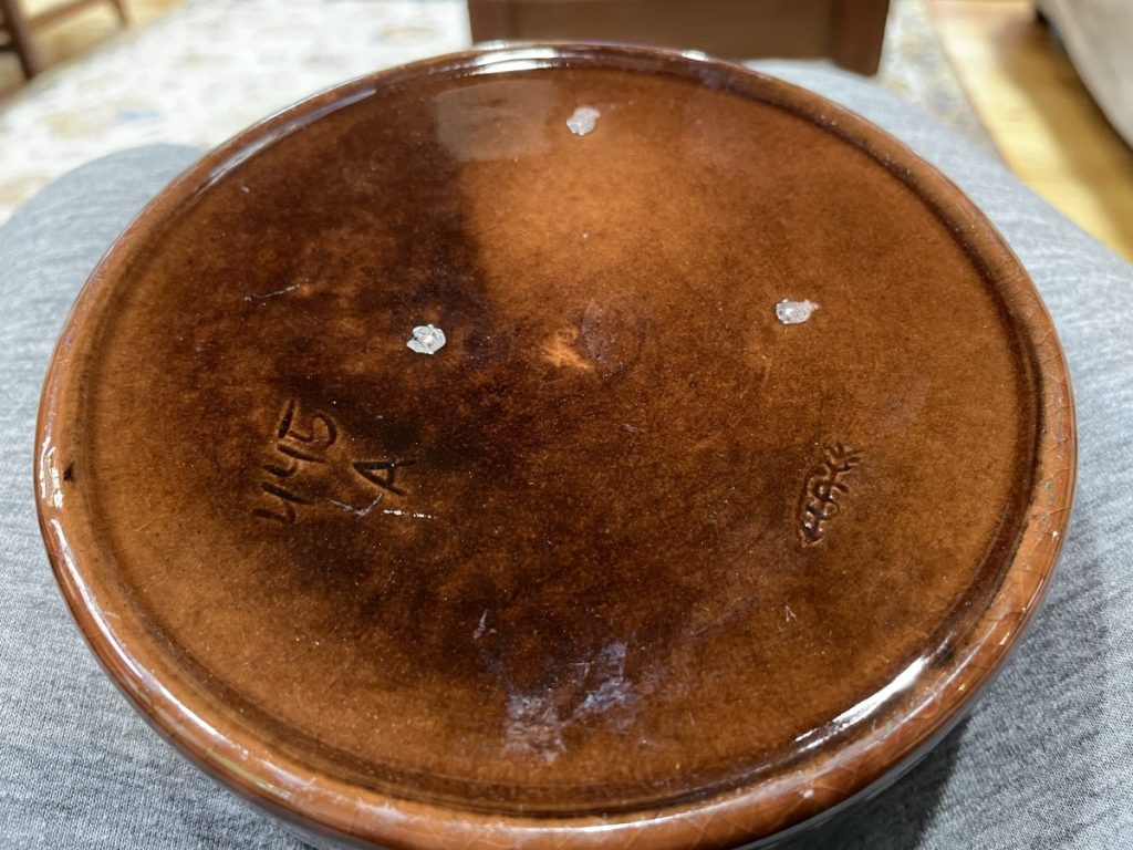 Top view of a brown ceramic bowl featuring a glossy finish and visible markings on the underside.